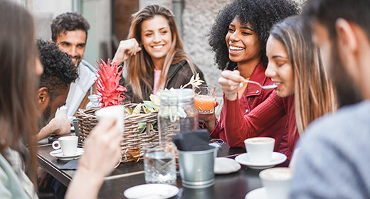 Friends gathered around a cafe table eating and talking