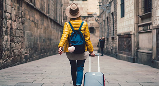 woman walking down a cobblestone alley while rolling a suitcase_520x280