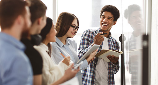 Group of teenage students looking at a whiteboard and taking notes in their notebooks