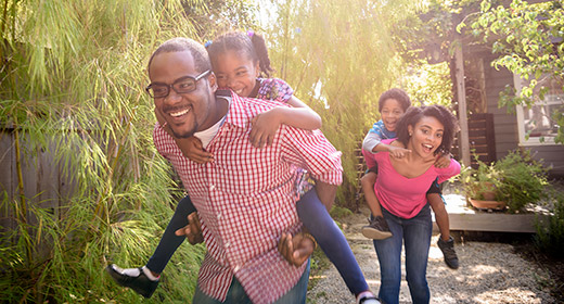 Parents in backyard giving two children piggyback rides