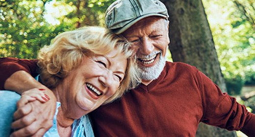 older couple hiking in the woods while talking and laughing