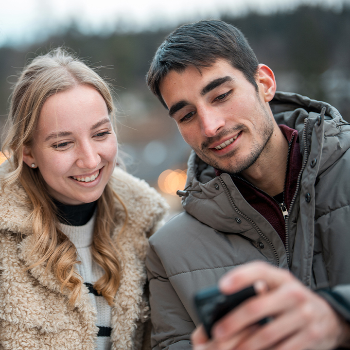 two friends looking at a phone together_720x720