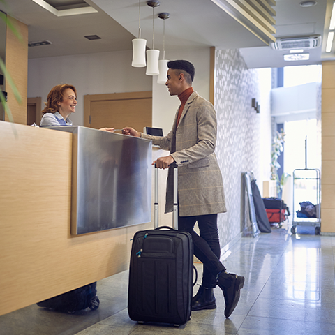 man checking into a hotel at the front desk_480x480