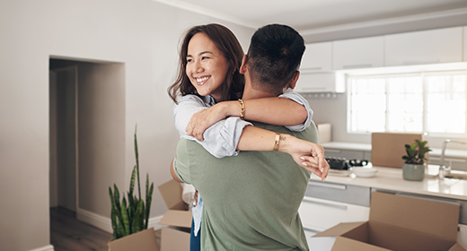 couple embracing in their new home surrounded by boxes 520x280