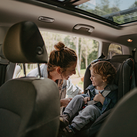 Mother strapping her young son into a carseat