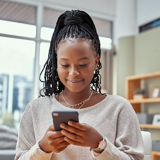 woman looking down at her phone and smiling