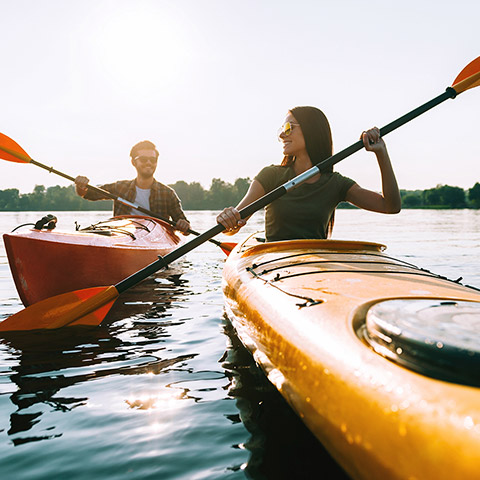 Man and woman kayaking on a lake in the early morning