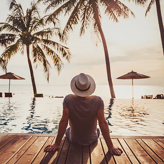 person sitting on the edge of a dock in a tropical paradise location