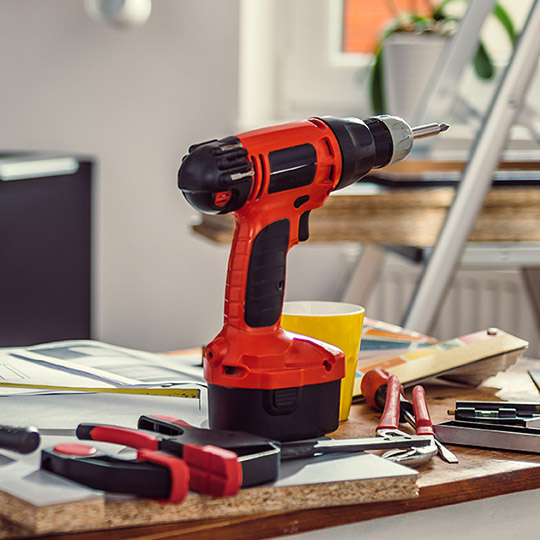 View of a workbench with a drill, pliers, hammer and other tools showing a home renovation project