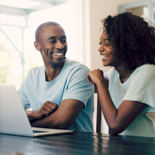 Couple sitting at their kitchen island talking and looking at a laptop