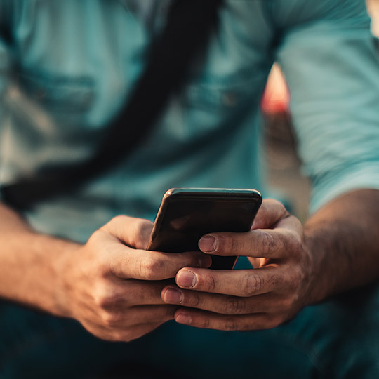 Close up of a man holding a mobile phone and typing on it