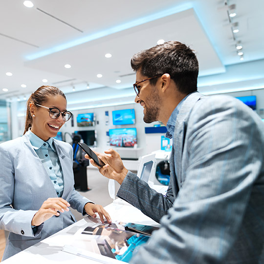 Man in a nice suit holding his phone at a checkout counter to purchase an item