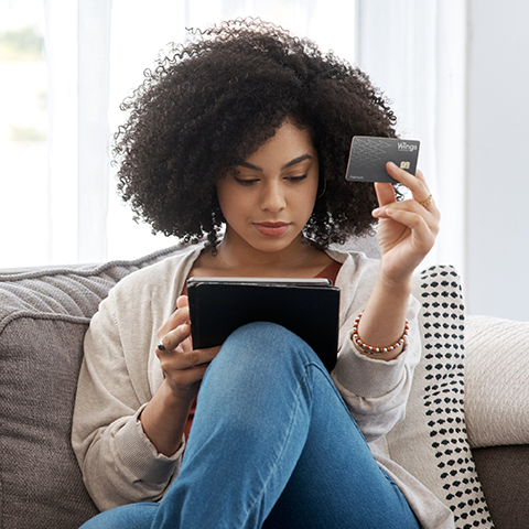 woman holding her tablet and wings platinum card_480x480