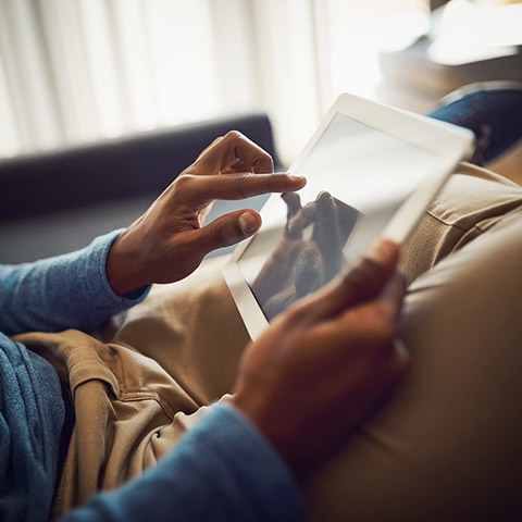 /getmedia/d09f314b 0775 48f9 881c d99796996238/man sitting on his couch with a tablet device in his hands 1