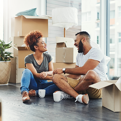 couple siting on the floor laughing and surrounded by boxes