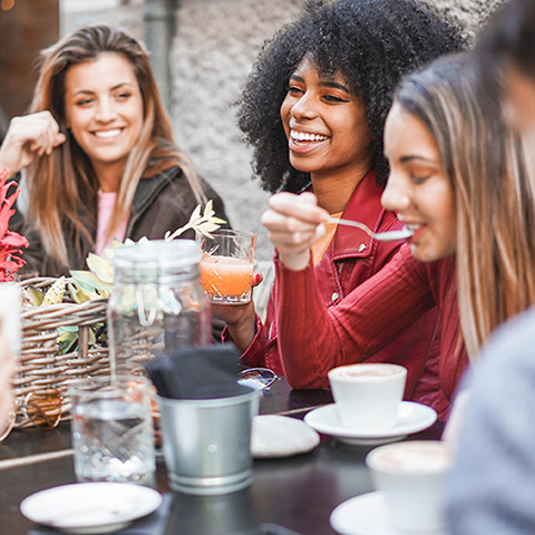 Friends gathered around a cafe table eating and talking