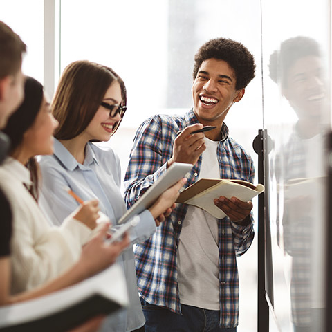 Group of teenage students looking at a whiteboard and taking notes in their notebooks