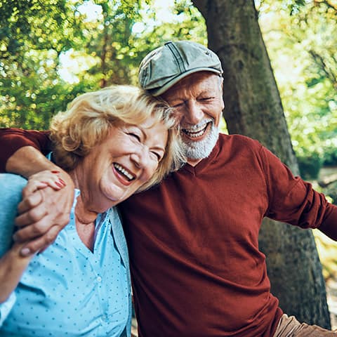 older couple hiking in the woods while talking and laughing