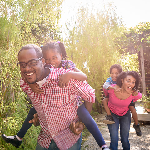 Parents in backyard giving two children piggyback rides