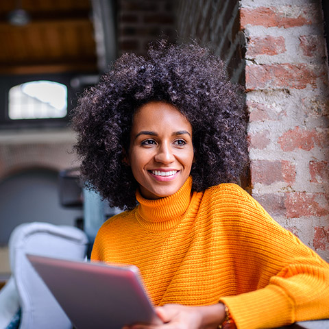 Woman sitting in a chair at a coffee shop with a tablet device